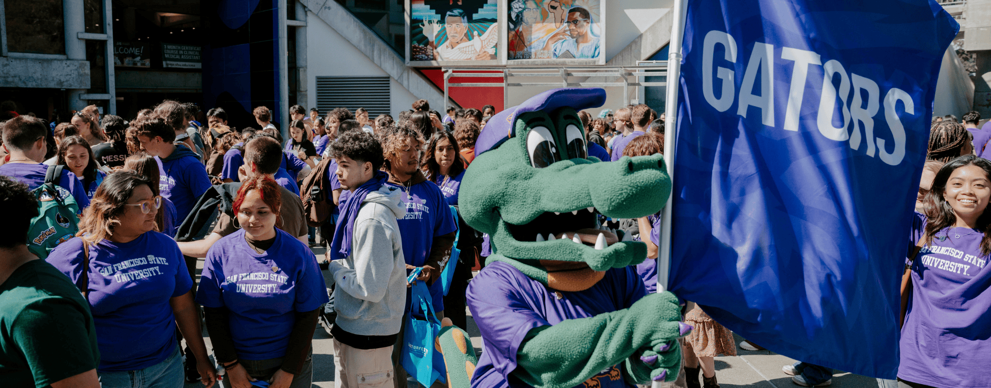 A crowd of students surround Alli the Gator at Orientation