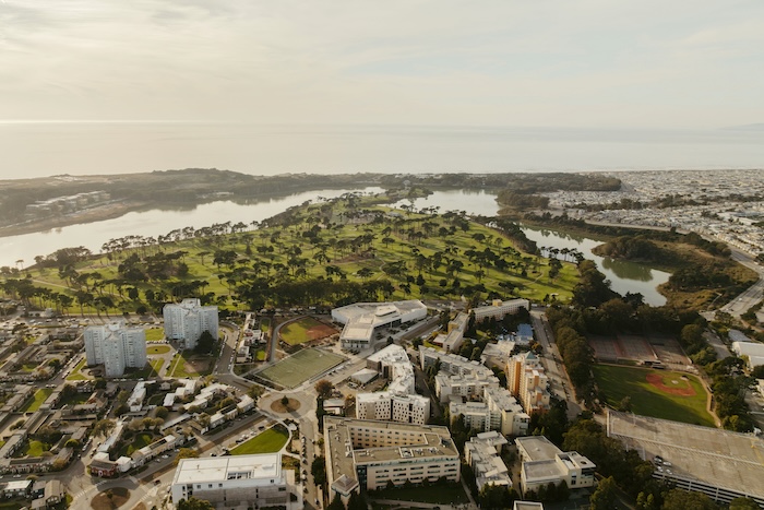 arial view of SFSU campus with trees, ocean, and buildings