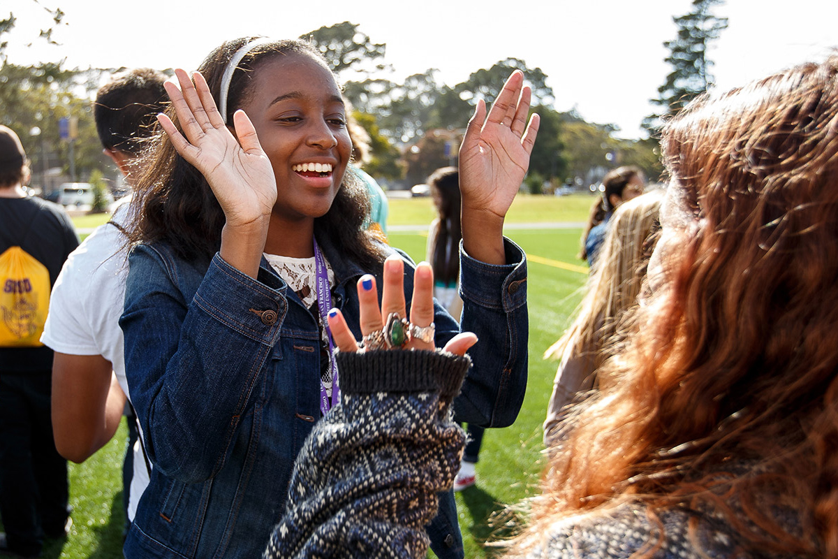 Two SF State students smiling and hi-fiving