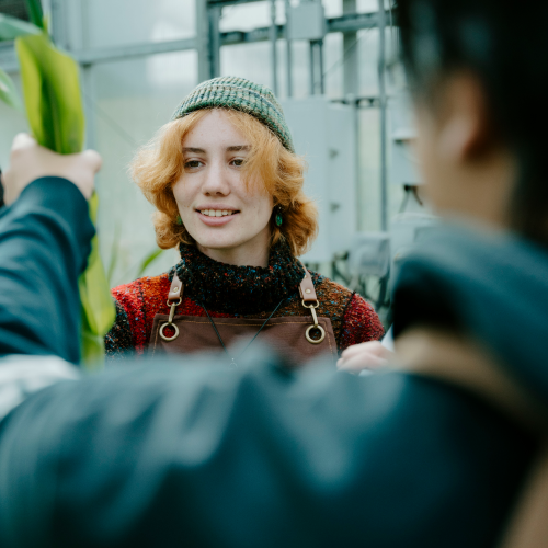 student wearing hat and apron grabbing green produce from another person