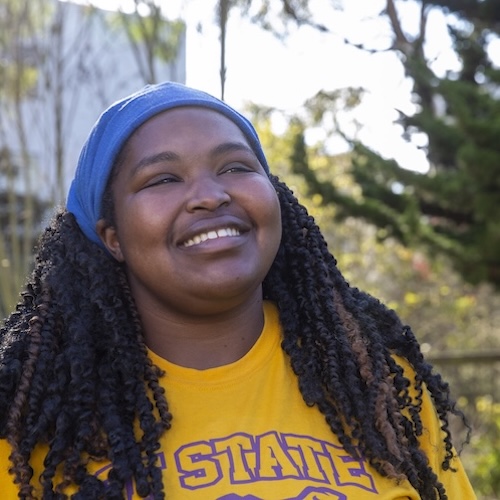 student smiling wearing gold SFSU shirt