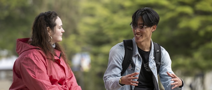 Male and Female students sitting on bench talking