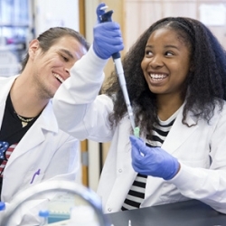 San Francisco State University student in lab coat holding a pipetin science lab